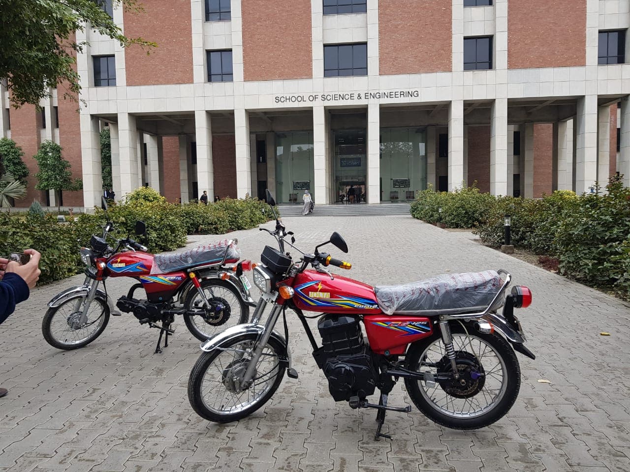 Two red Jolta electric motorcycles displayed outside LUMS
